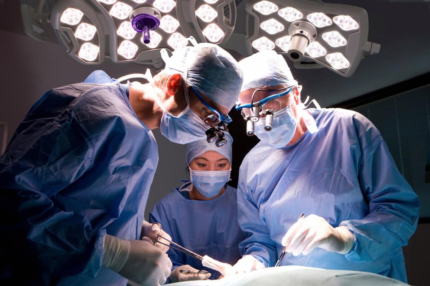 Surgical team performing a proctology procedure under operating room lights