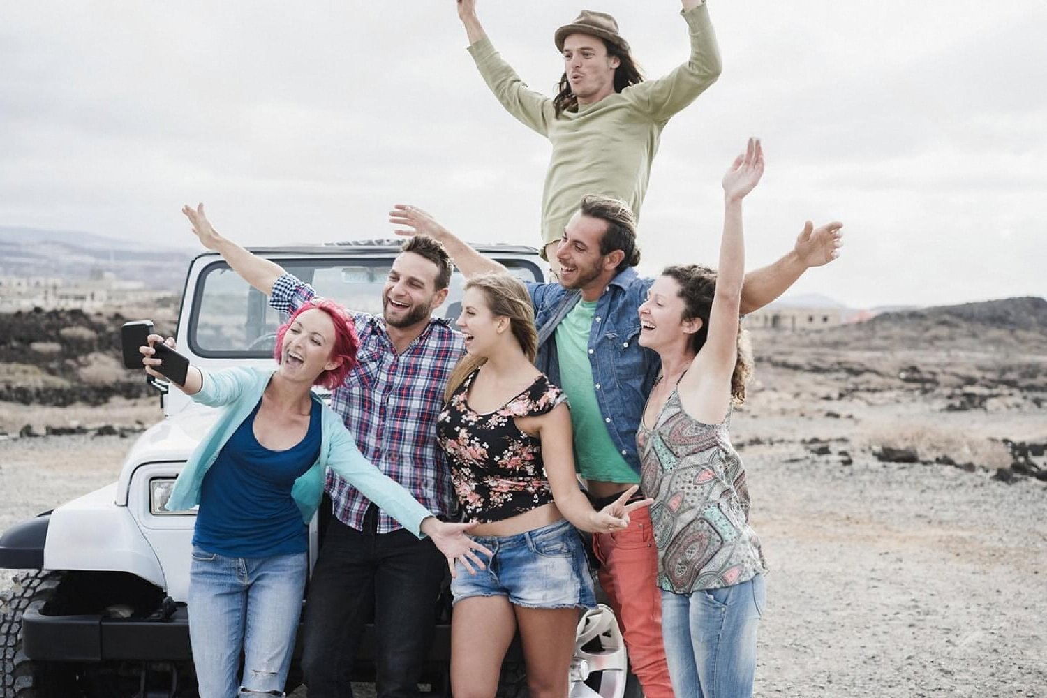 Group of friends celebrating next to a rental 4x4 in the Australian outback